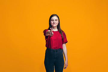 Image showing The happy teen girl pointing to you, half length closeup portrait on orange background.