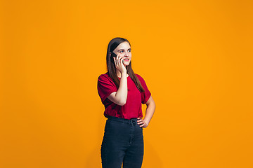 Image showing The happy teen girl standing and smiling against orange background.