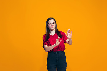 Image showing Let me think. Doubtful pensive teen girl with thoughtful expression making choice against orange background