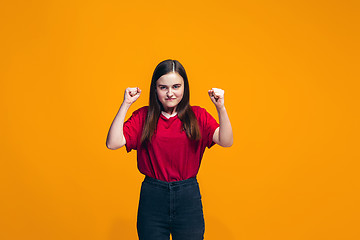 Image showing Portrait of angry teen girl on a orange studio background