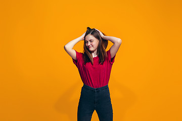 Image showing The happy teen girl standing and smiling against orange background.