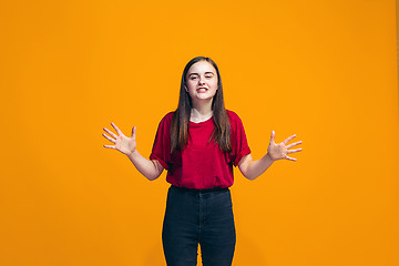 Image showing The happy teen girl standing and smiling against orange background.