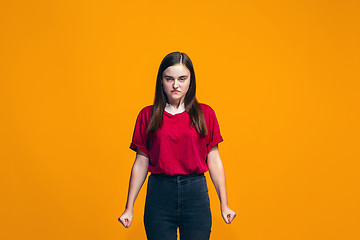 Image showing Portrait of angry teen girl on a orange studio background