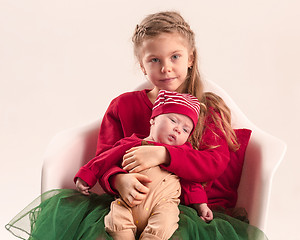 Image showing Happy little teen girl holding his newborn baby little sister. Family love.