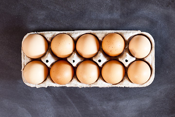 Image showing Farm chicken eggs in cardboard container on black background.