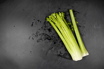 Image showing Fresh green organic celery and water on black background.
