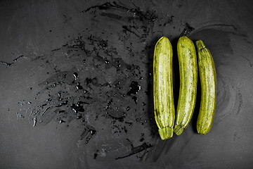 Image showing Fresh green wet zucchini on blackboard background. 