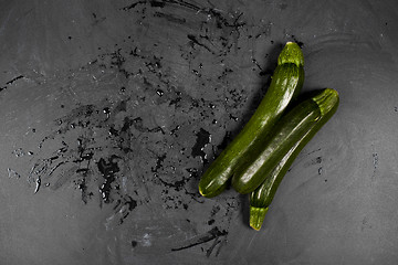 Image showing Fresh green wet zucchini on blackboard background. 