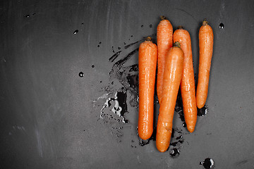 Image showing Fresh organic wet carrots on black background.