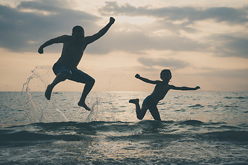 Image showing Father and son playing on the beach at the sunset time.