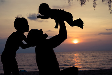 Image showing Father and two sons  playing on the beach at the sunset time.