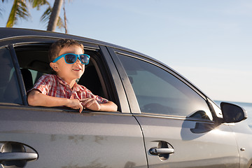 Image showing One happy little boy sitting in the car at the day time.