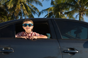 Image showing One happy little boy sitting in the car at the day time.