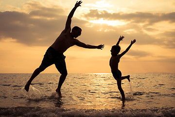 Image showing Father and son playing on the beach at the sunset time.