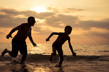 Image showing Father and son playing on the beach at the sunset time.