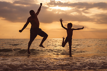 Image showing Father and son playing on the beach at the sunset time.