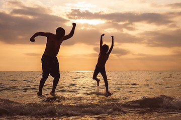 Image showing Father and son playing on the beach at the sunset time.