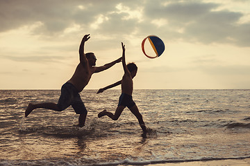 Image showing Father and son playing on the beach at the sunset time.