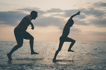 Image showing Father and son playing on the beach at the sunset time.