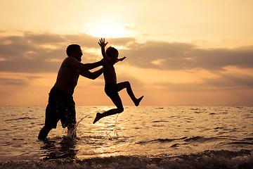 Image showing Father and son playing on the beach at the sunset time.