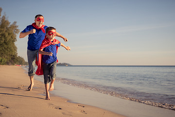 Image showing Father and son playing superhero on the beach at the day time.