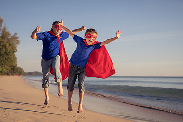 Image showing Father and son playing superhero on the beach at the day time.