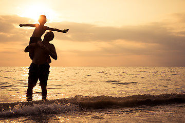 Image showing Father and son playing on the beach at the sunset time.