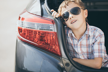 Image showing One happy little boy sitting in the car at the day time.