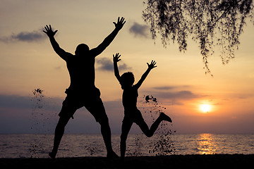 Image showing Father and son playing on the beach at the sunset time.