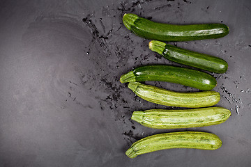 Image showing Fresh green wet zucchini on blackboard background.