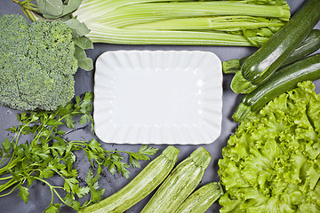 Image showing Variety of green vegetables and white ceramic plate. 