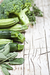 Image showing Variety of green organic vegetables on rustic wooden background.