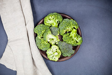 Image showing Fresh green organic broccoli in brown plate and linen napkin.