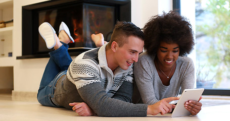 Image showing multiethnic couple using tablet computer on the floor