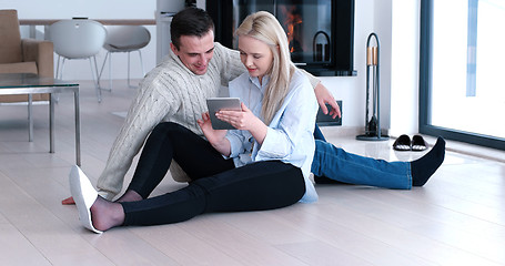 Image showing Young Couple using digital tablet on the floor