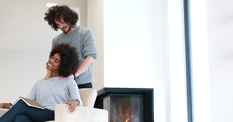 Image showing multiethnic couple hugging in front of fireplace