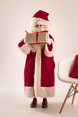 Image showing The happy girl in santa claus costume with gift box at studio