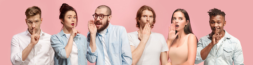 Image showing The young men and women whispering a secret behind hands over pink background