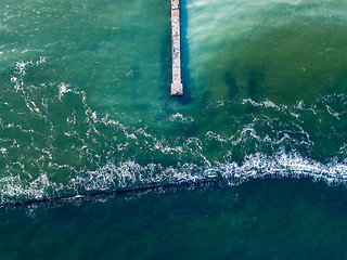 Image showing Natural sea background with turquoise water. Top aerial view from drone to moles and jetty with foam waves. Copy space.