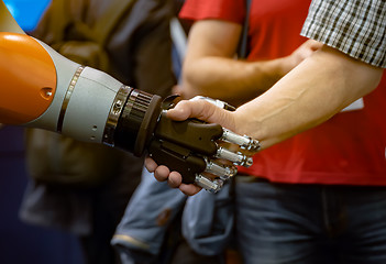 Image showing Hand of a man shaking hands with a Android robot.