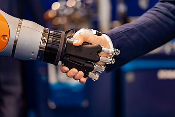 Image showing Hand of a businessman shaking hands with a Android robot.