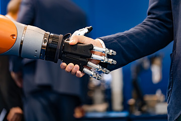 Image showing Hand of a businessman shaking hands with a Android robot.