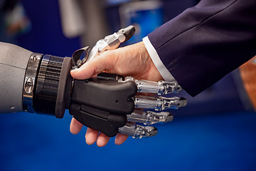 Image showing Hand of a businessman shaking hands with a Android robot.