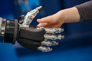 Image showing Hand of a businesswoman shaking hands with a Android robot.