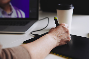 Image showing Woman designer working at a laptop with a graphics tablet.