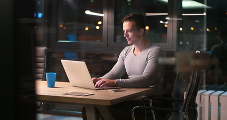 Image showing man working on laptop in dark office