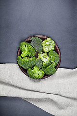 Image showing Fresh green organic broccoli in brown plate and linen napkin.