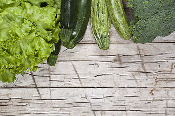 Image showing Variety of green organic vegetables on rustic wooden background.