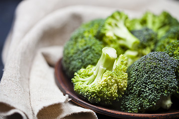 Image showing Fresh green organic broccoli in brown plate and linen napkin.