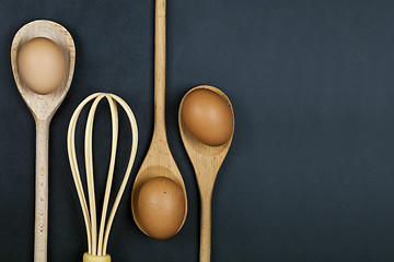 Image showing Eggs, wooden spoon and whisker. Kitchen utensil for cake, pastry